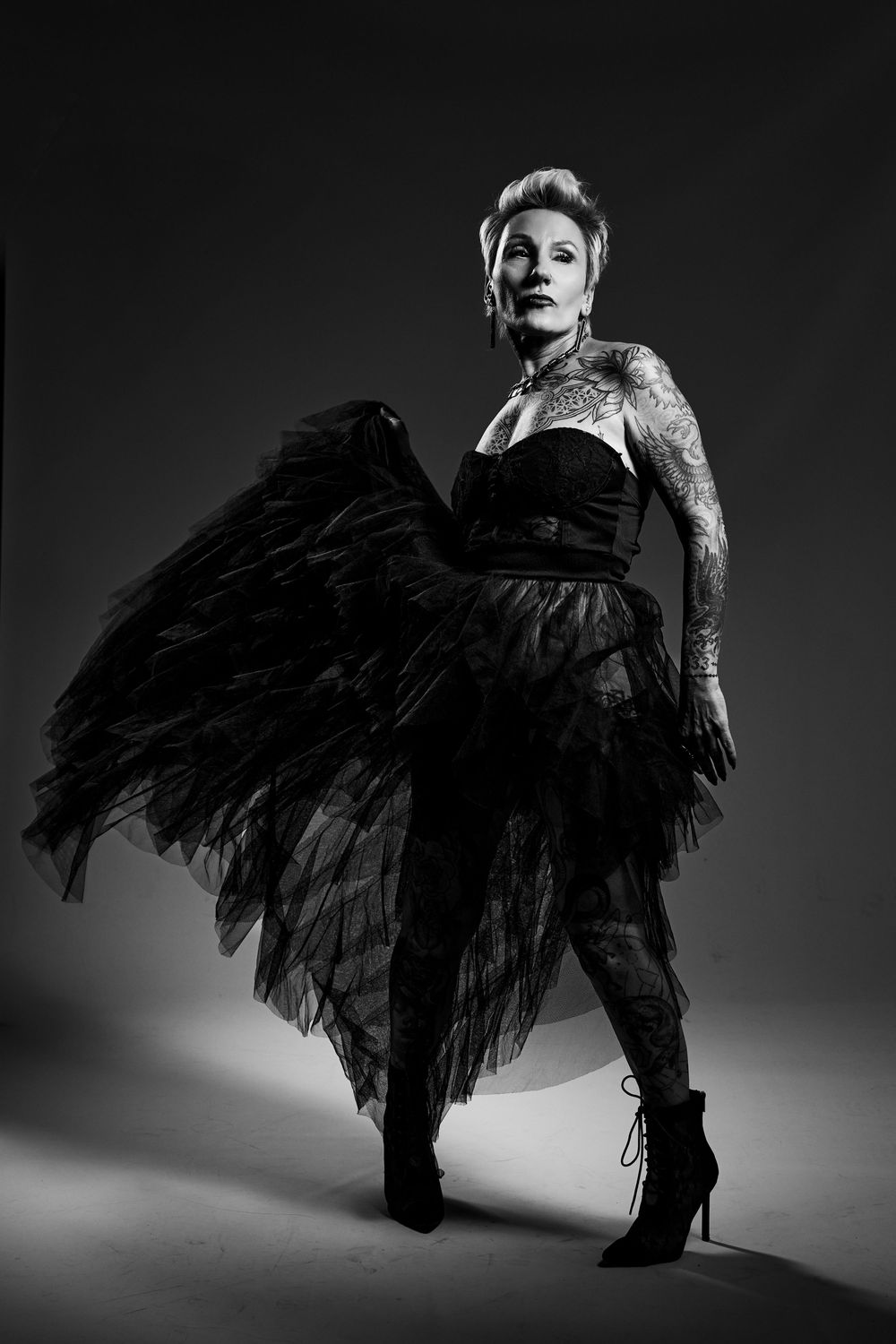 Fashion photo sequence of model in dramatic black feathered gown posing dramatically against light background.