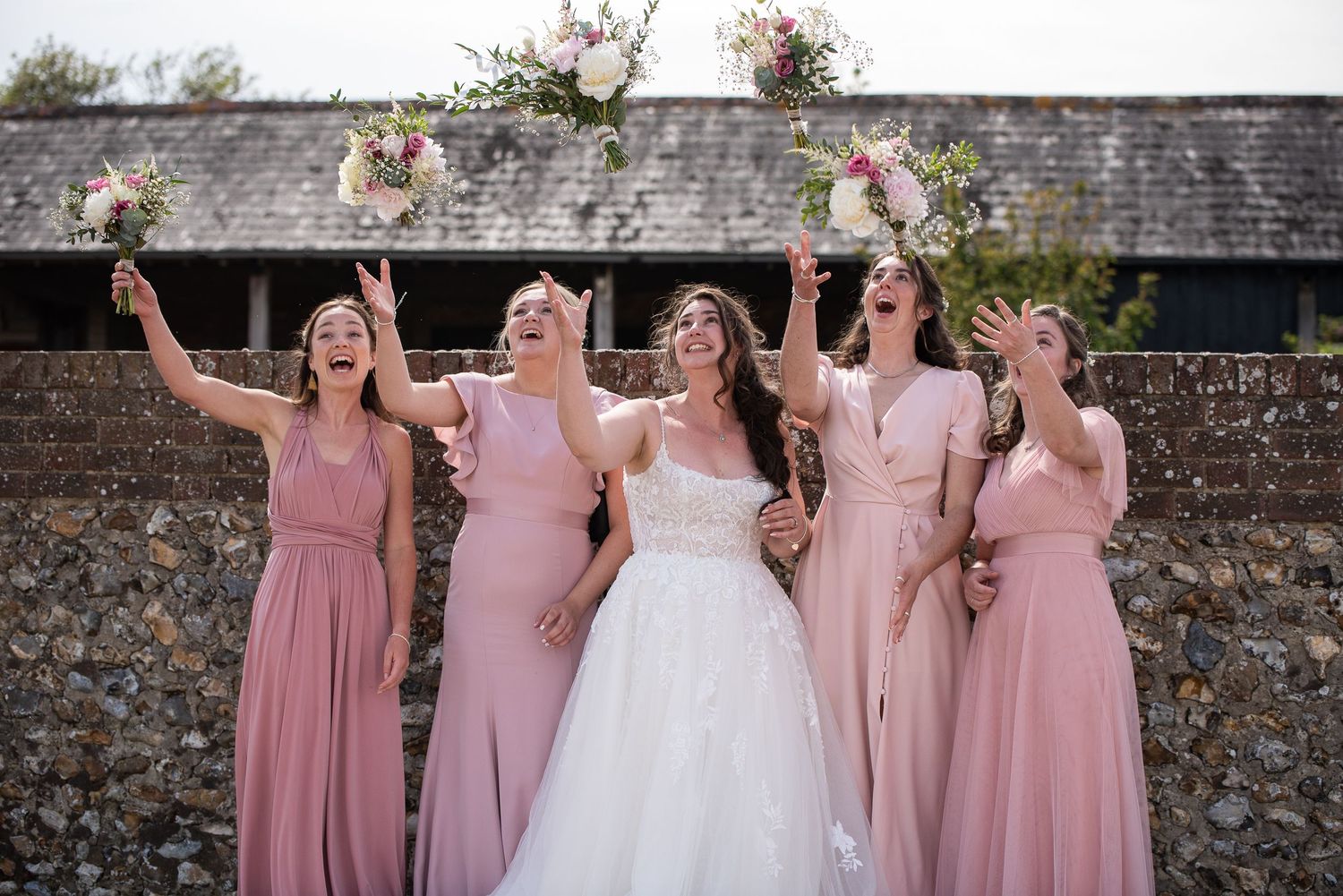 Bride and four bridesmaids throw bouquets in the air