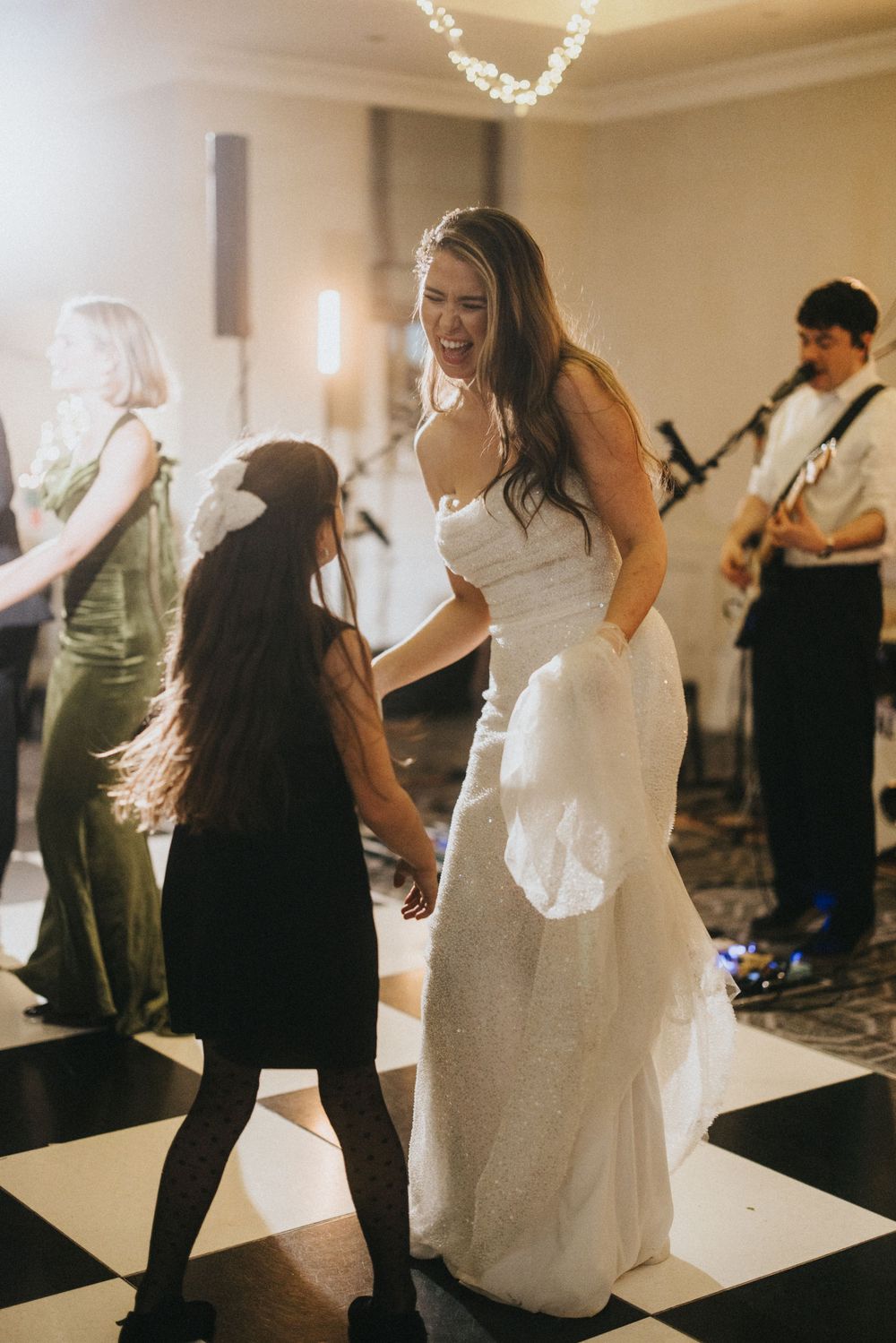 Wedding guests dancing together at a reception with a white dress flowing in motion on the dance floor.