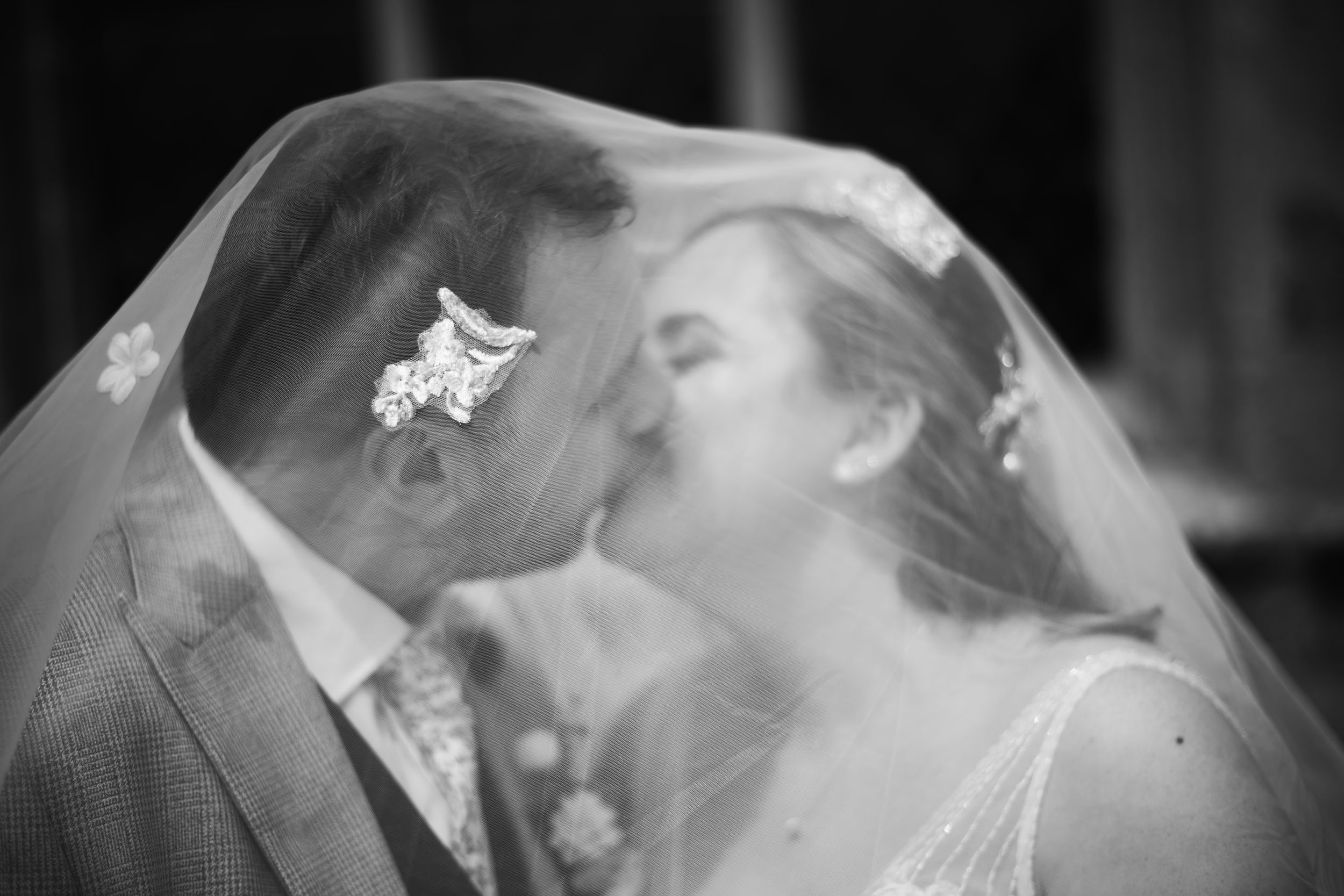 A romantic black and white photo shows a couple sharing a tender kiss on their wedding day.