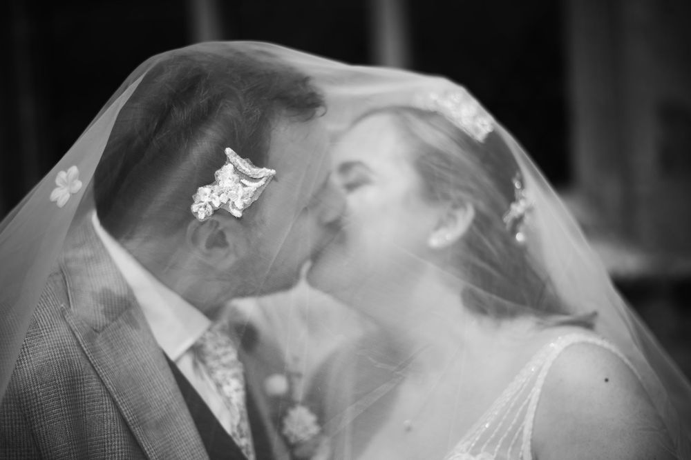 A romantic black and white photo shows a couple sharing a tender kiss on their wedding day.