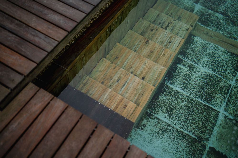Moderne Holzterrasse mit türkisfarbenem Pool-Wasserspiel.