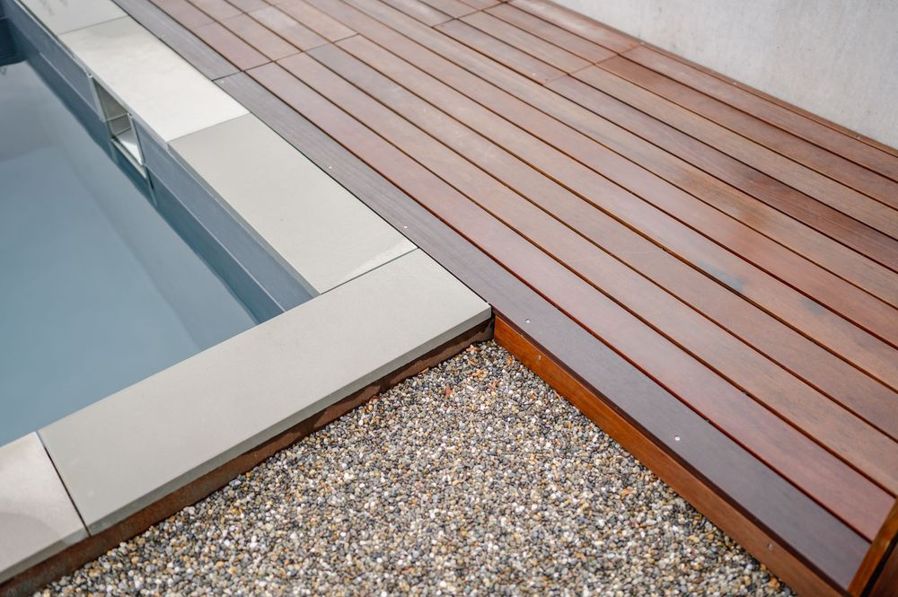 Modernes Terrassendesign mit Holzplanken und Kieselsteinbordüre.