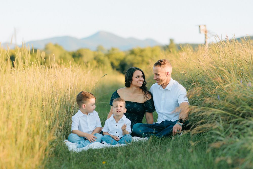 Family enjoying a relaxed outdoor photo session in a golden grass field during sunset.