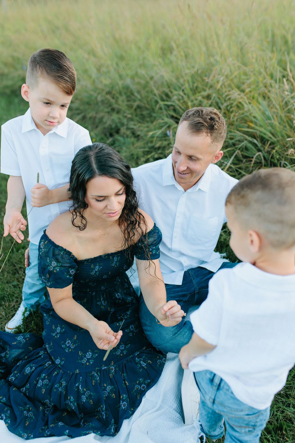 Candid family moments captured while playing together in tall grass during a summer photoshoot.