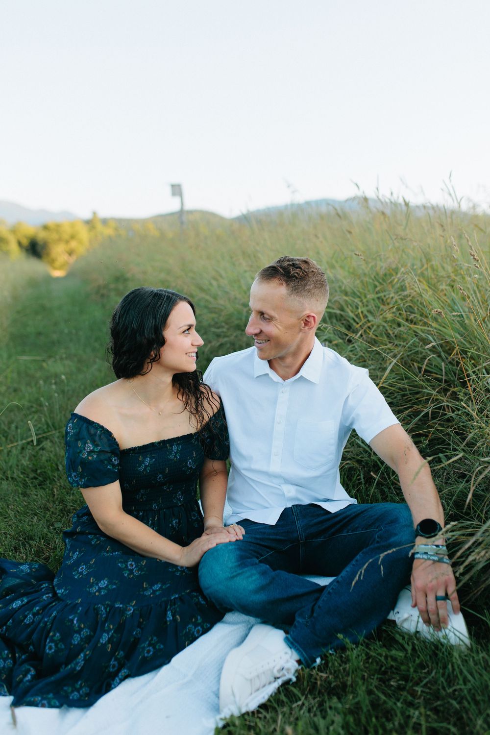 Couple shares intimate moments while relaxing in a grassy field at sunset.