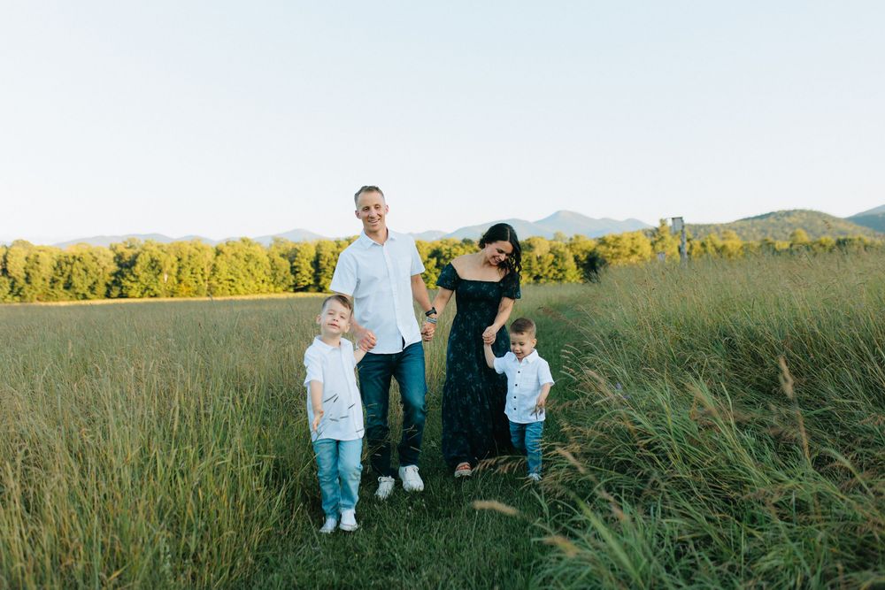 A group enjoying a warm afternoon in a grassy field with mountains and autumn trees in the background.
