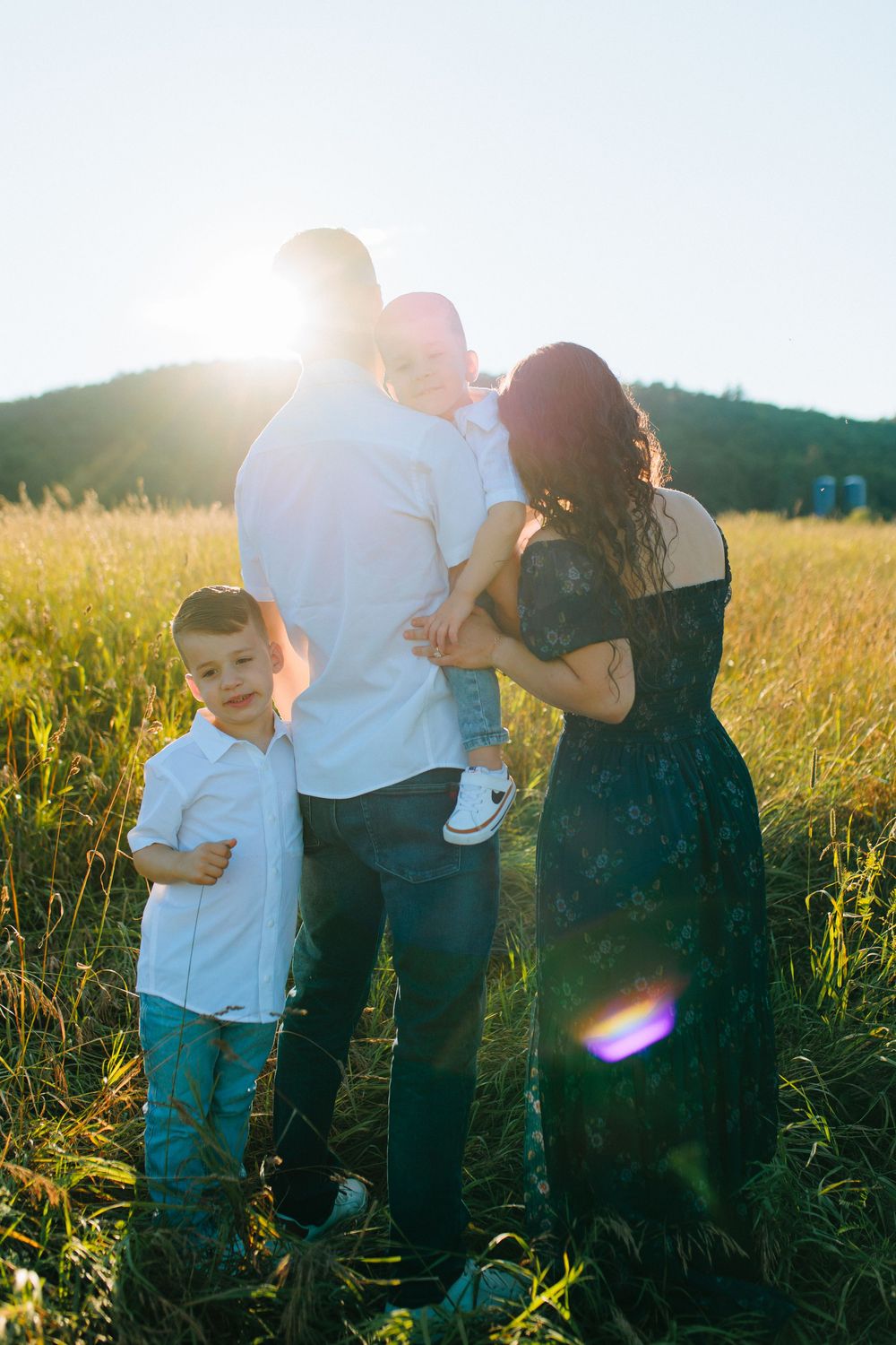 Family plays and laughs together in a sun-drenched meadow during golden hour.