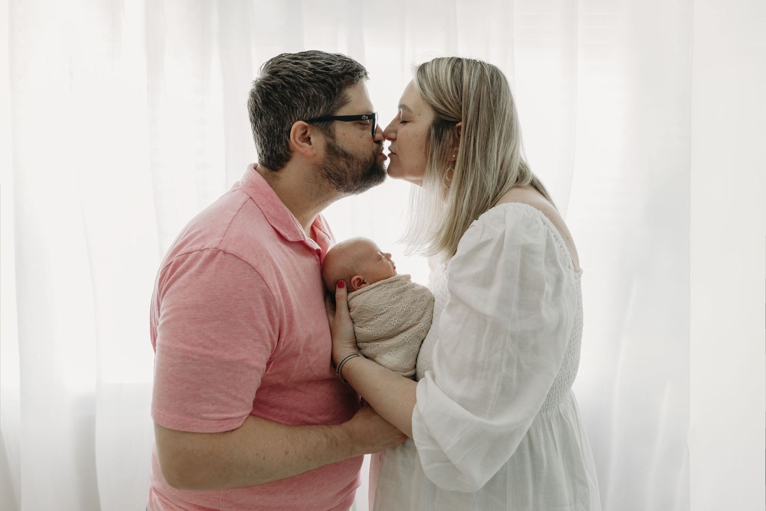 A couple shares an intimate romantic moment together during newborn photos with parents in Tampa