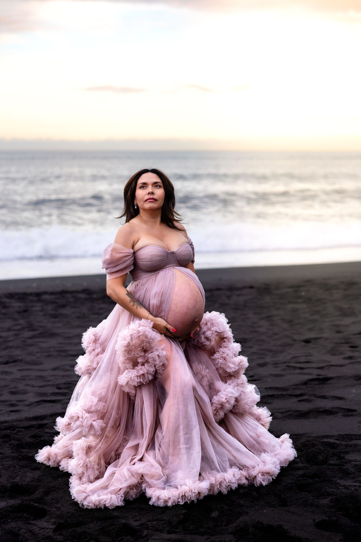 Gravid kvinna i rosa tyllklänning på strand