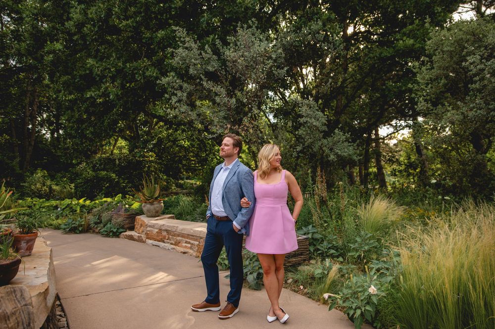 Couple walking on a curved garden path surrounded by lush greenery and landscaped borders.