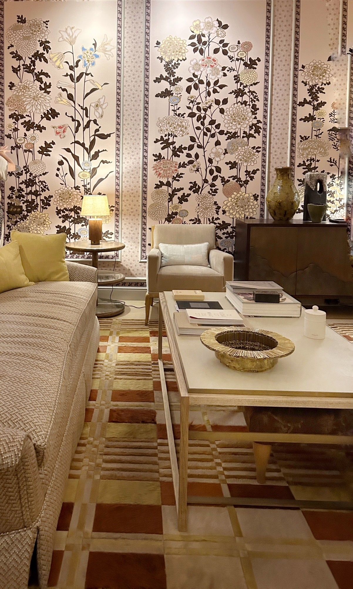Modern living room with floral wallpaper, cream furniture, geometric rug, and clean lined coffee table with ambient lighting.