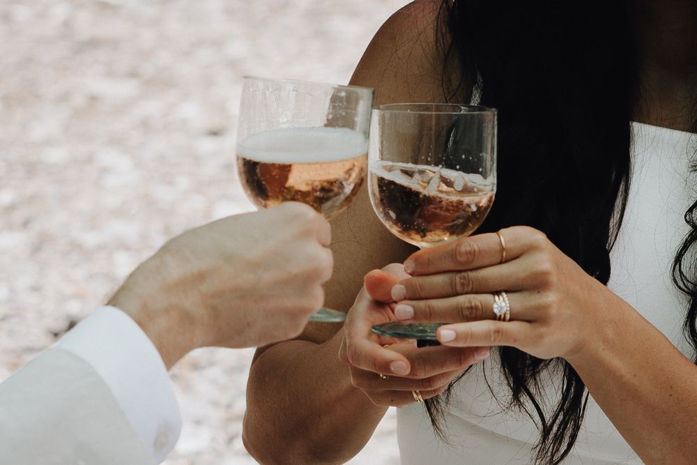 A close-up shot of hands clinking whiskey glasses in a toast against a blurred background.