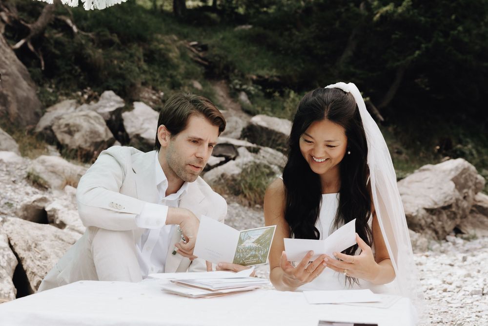 Couple sharing a romantic picnic on a white sandy beach with snacks and drinks.