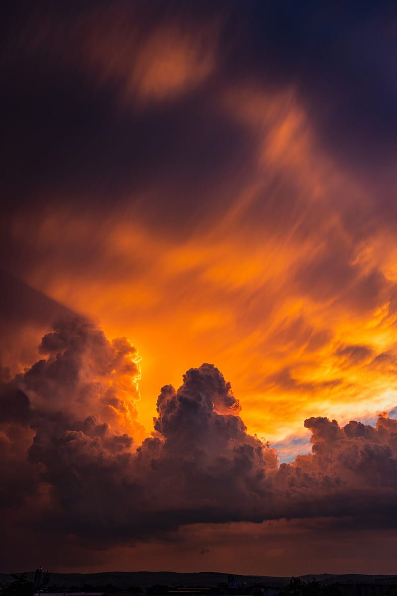 Stunning aerial view of golden sunset illuminating fluffy clouds above with vibrant orange and yellow hues.
