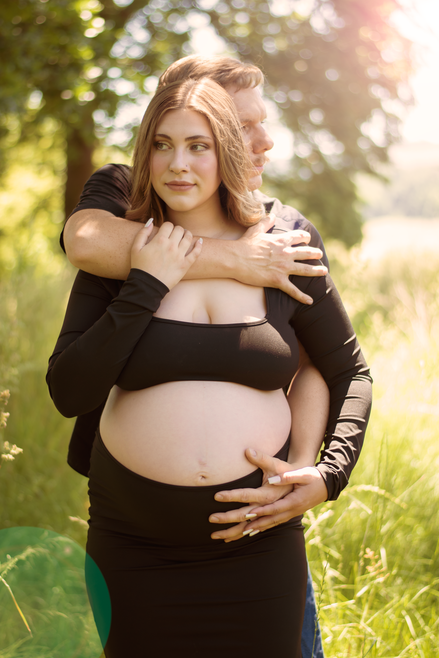 Natural light maternity photography featuring intimate moments in a golden outdoor setting.