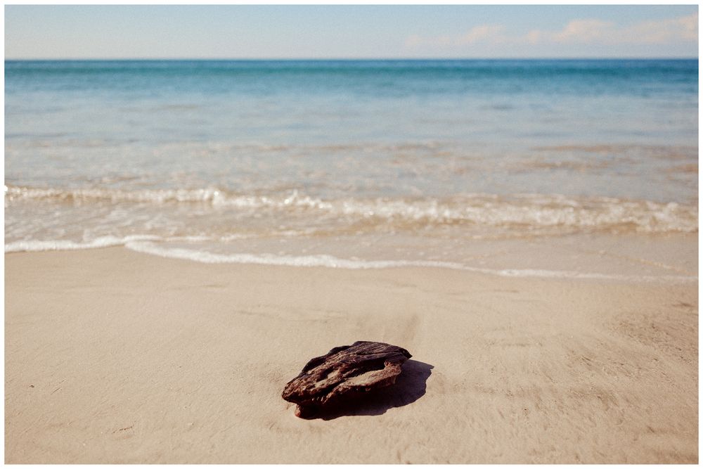 Peaceful beach shoreline with gentle waves lapping at the sandy shore during a calm summer day.