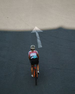 Aerial view of cyclists riding along a dark mountain road in a line formation.