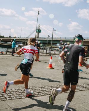 Athletes perform burpee exercises on a concrete surface during an outdoor fitness competition.