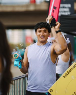 Athlete in gray sleeveless shirt holding a bubble blower toy during an outdoor event.