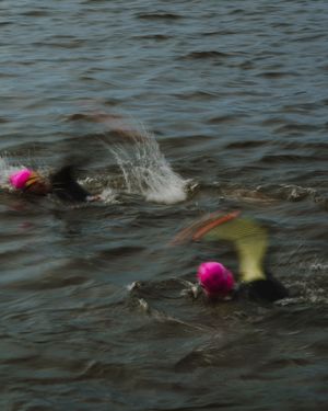 A sequence of swimming motions captured in dark waters showing a swimmer doing freestyle strokes.