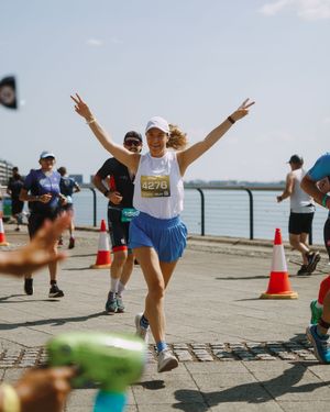Runner celebrating with victory signs during a waterfront marathon event.
