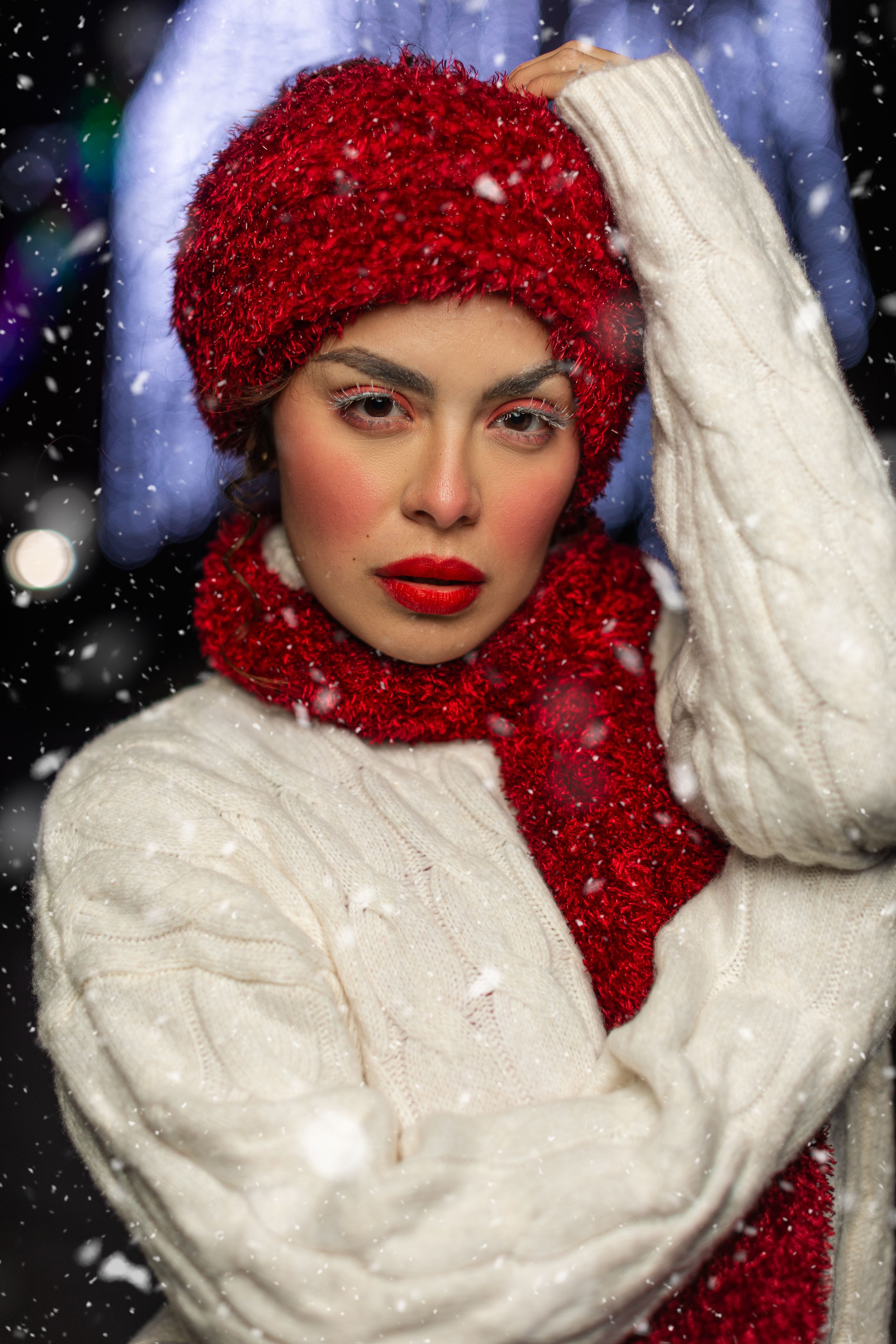Fashion portrait with bright red hair and a cozy white winter sweater against a snowy night backdrop.