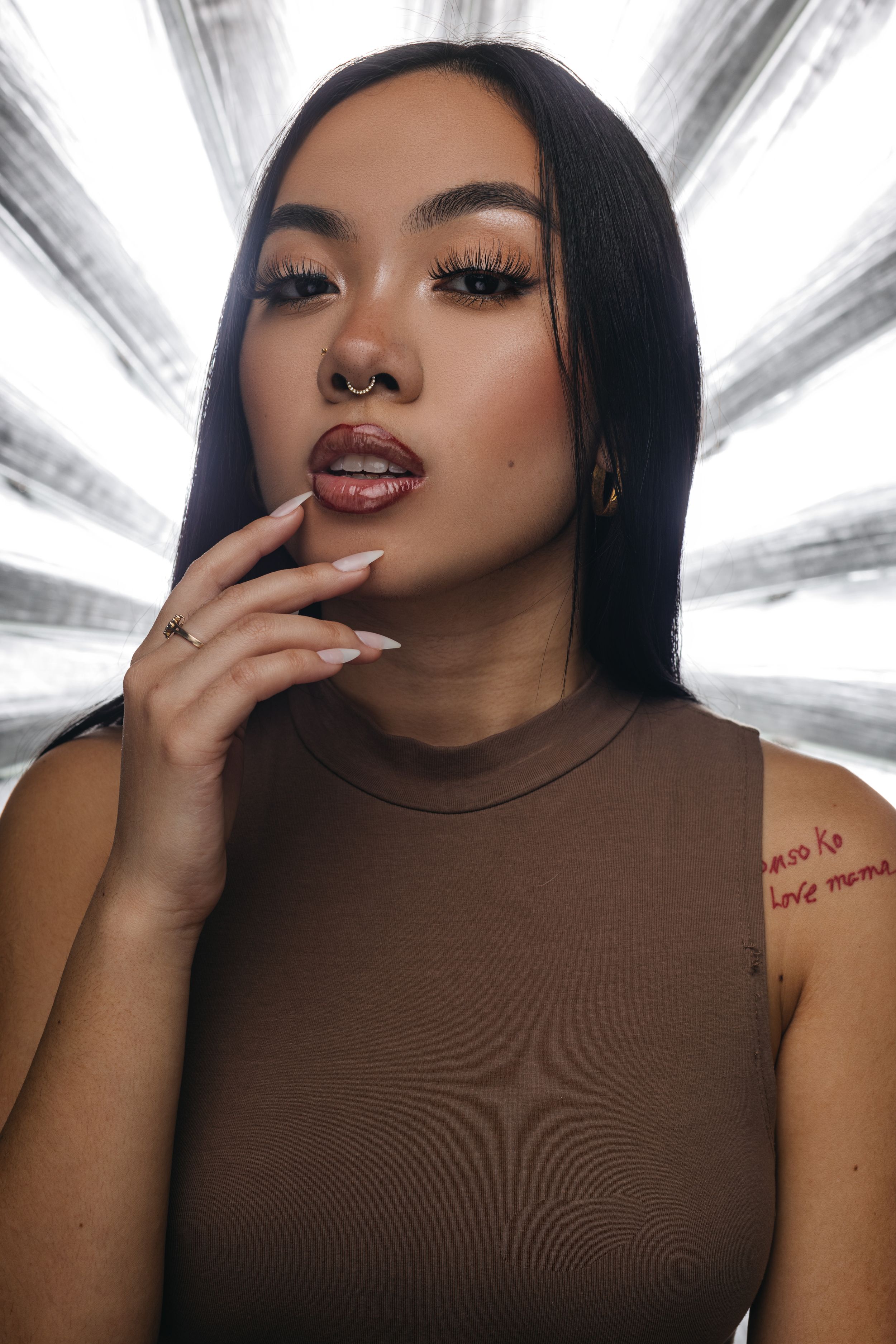 A person in a brown sheer turtleneck poses for a sultry photo series against a white background.