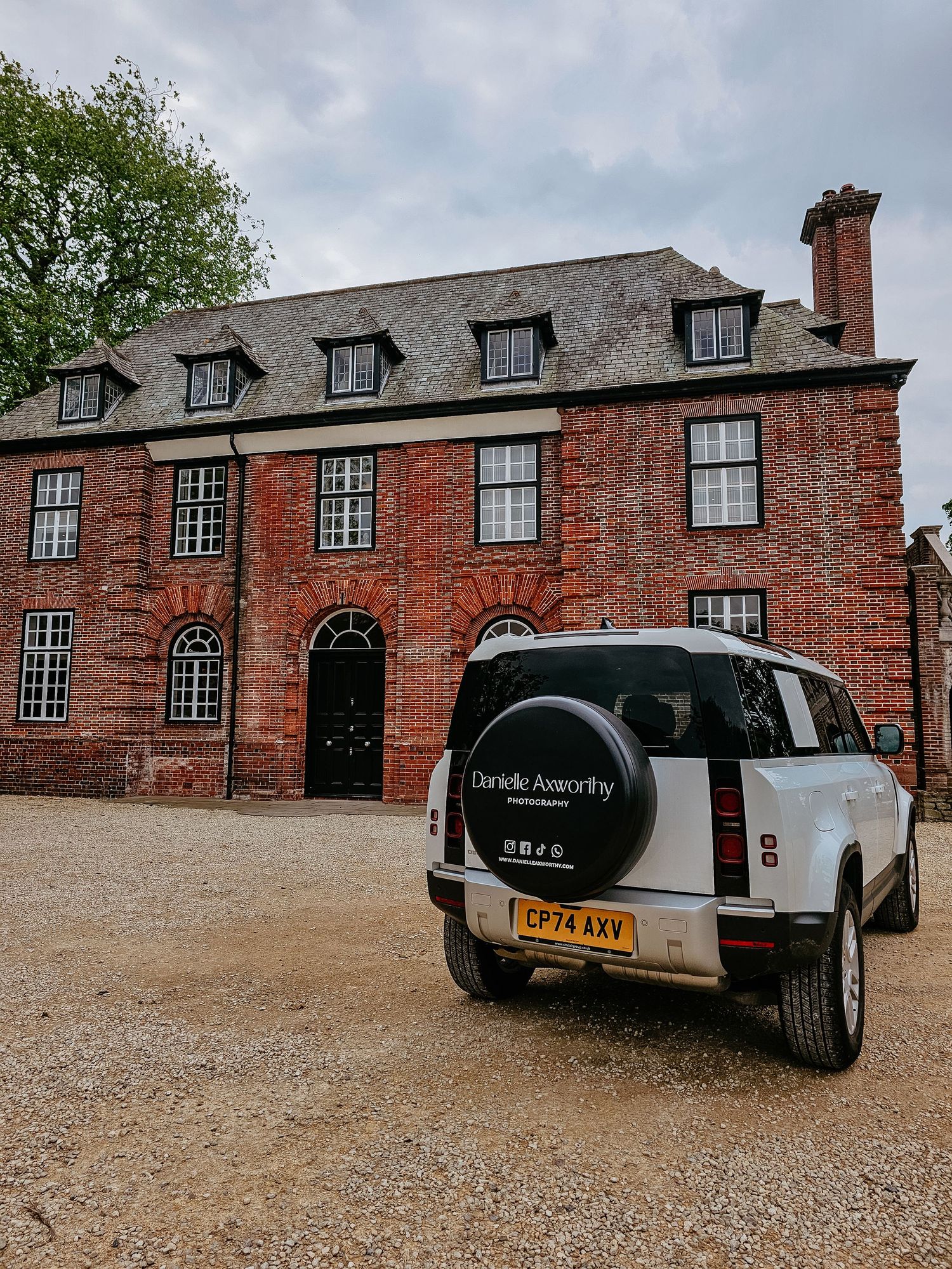Multiple views of a black car parked in front of a red brick historic building with dormer windows and tall chimneys.