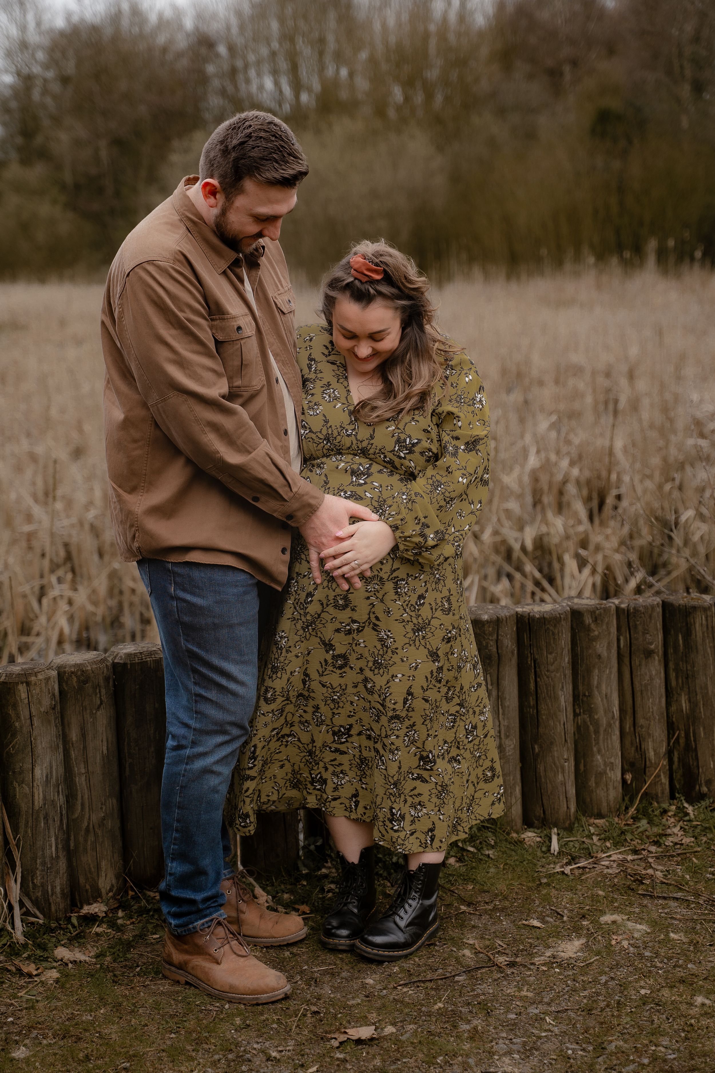 A parent and child share a tender moment together on a rustic wooden fence in a natural outdoor setting.