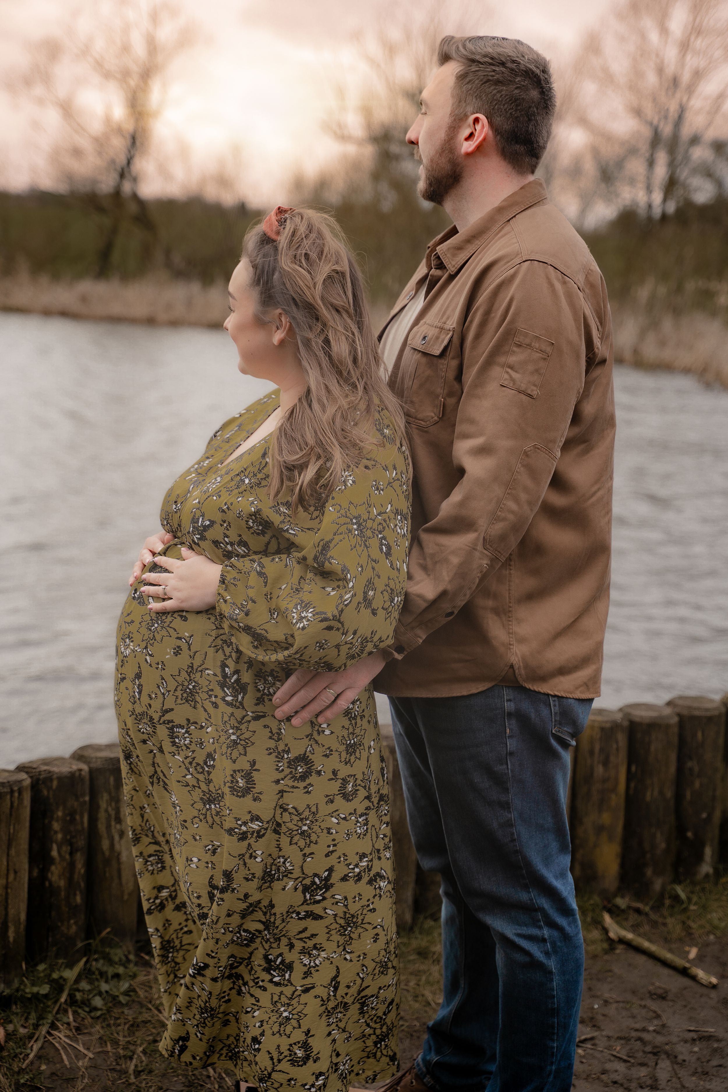 Expecting couple shares tender moments by a lake during sunset in a series of romantic maternity photos.