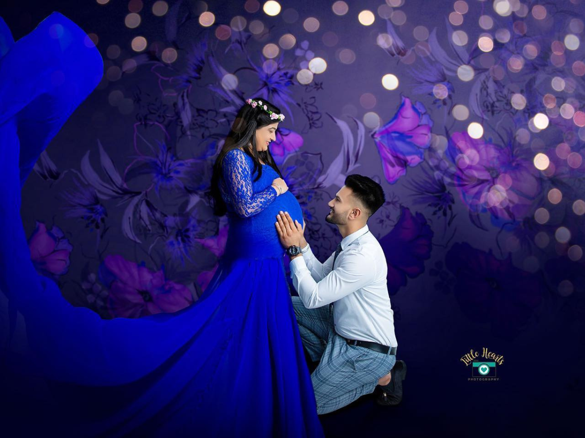 A couple shares a romantic dance together at a wedding reception illuminated by dark blue lighting and bokeh effects.
