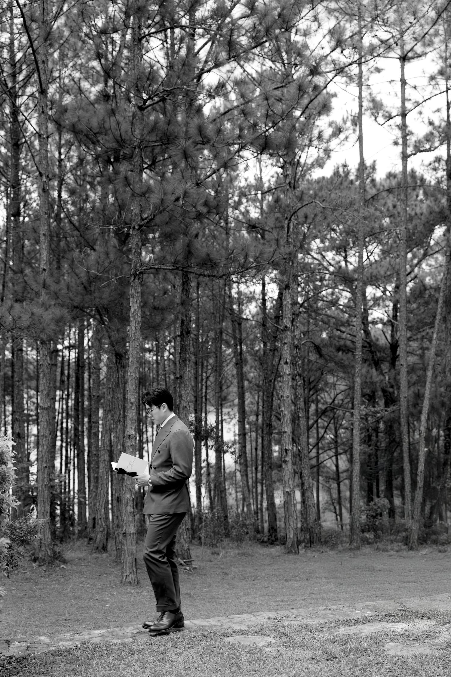 Black and white portrait of groom rehearsing wedding vows outdoors in pine forest.
