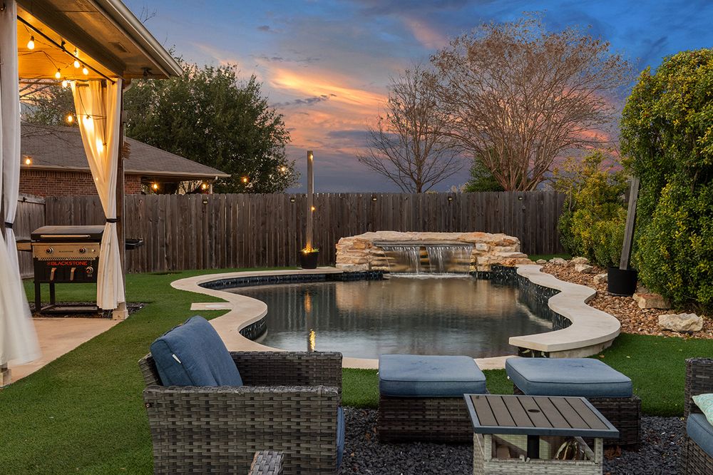 Backyard patio with outdoor furniture and a lake view at sunset creates a serene outdoor living space.