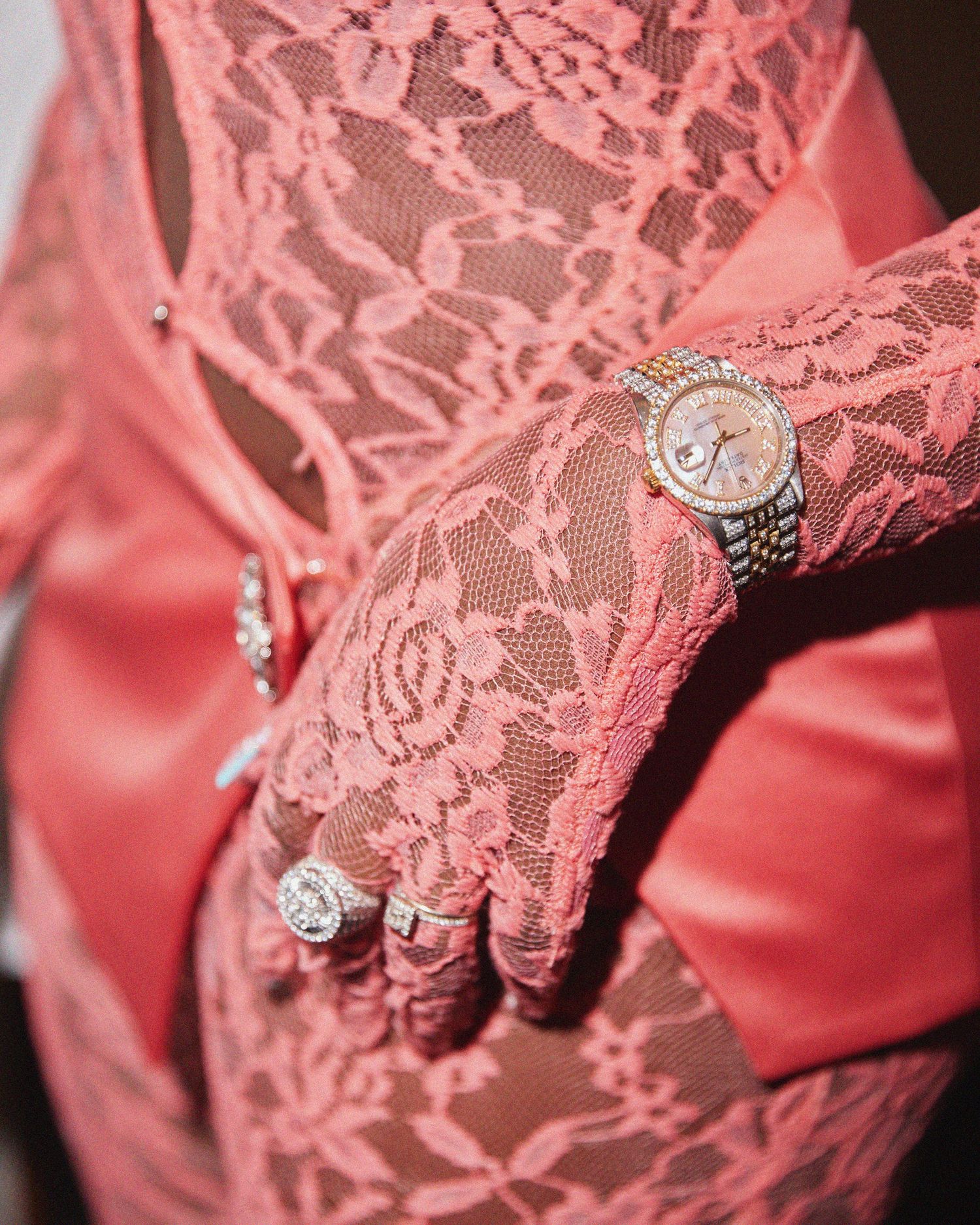 Coral pink lace fabric adorned with delicate rhinestone embellishments and intricate floral patterns.