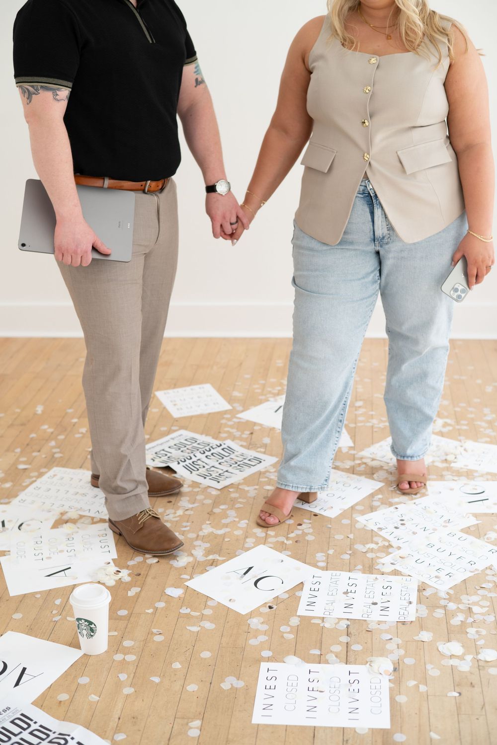 People standing on wooden floor covered with scattered paper and text.