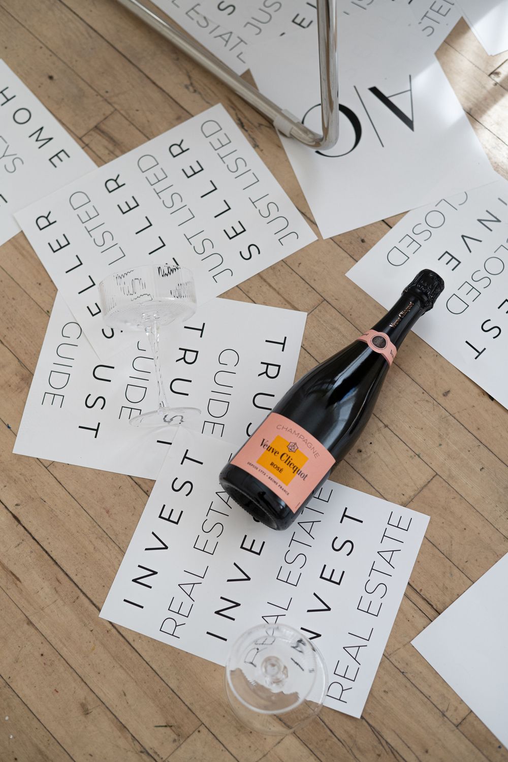 Letters and text scattered on a wooden floor with a dark bottle in the corner.