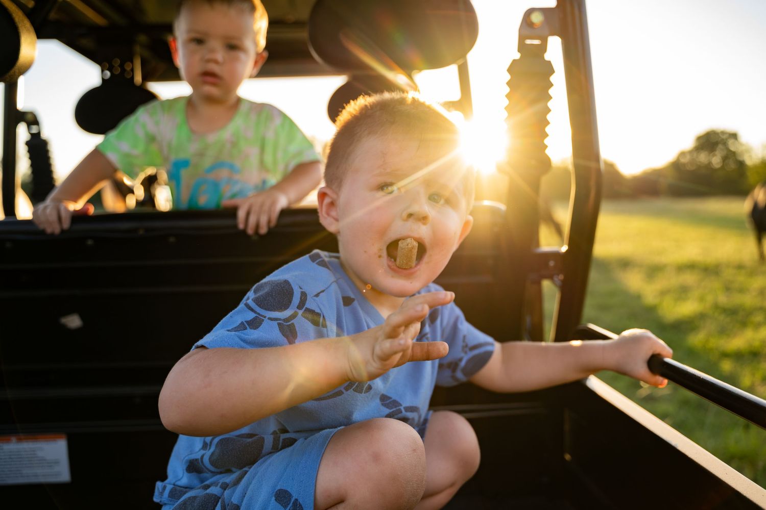 Farm kid playing and eating feed pellets in a golden field, real life family photography outside of Tulsa, Oklahoma