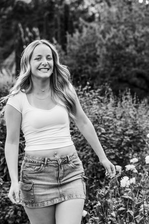 A sequence of black and white portraits of someone in denim and white top posing playfully in a garden setting.