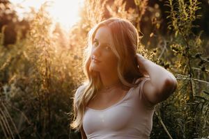 A sunlit portrait in tall grass and wildflowers during golden hour with soft, dreamy lighting.