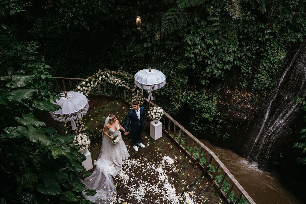 An outdoor wedding venue decorated with white umbrellas and string lights at dusk.