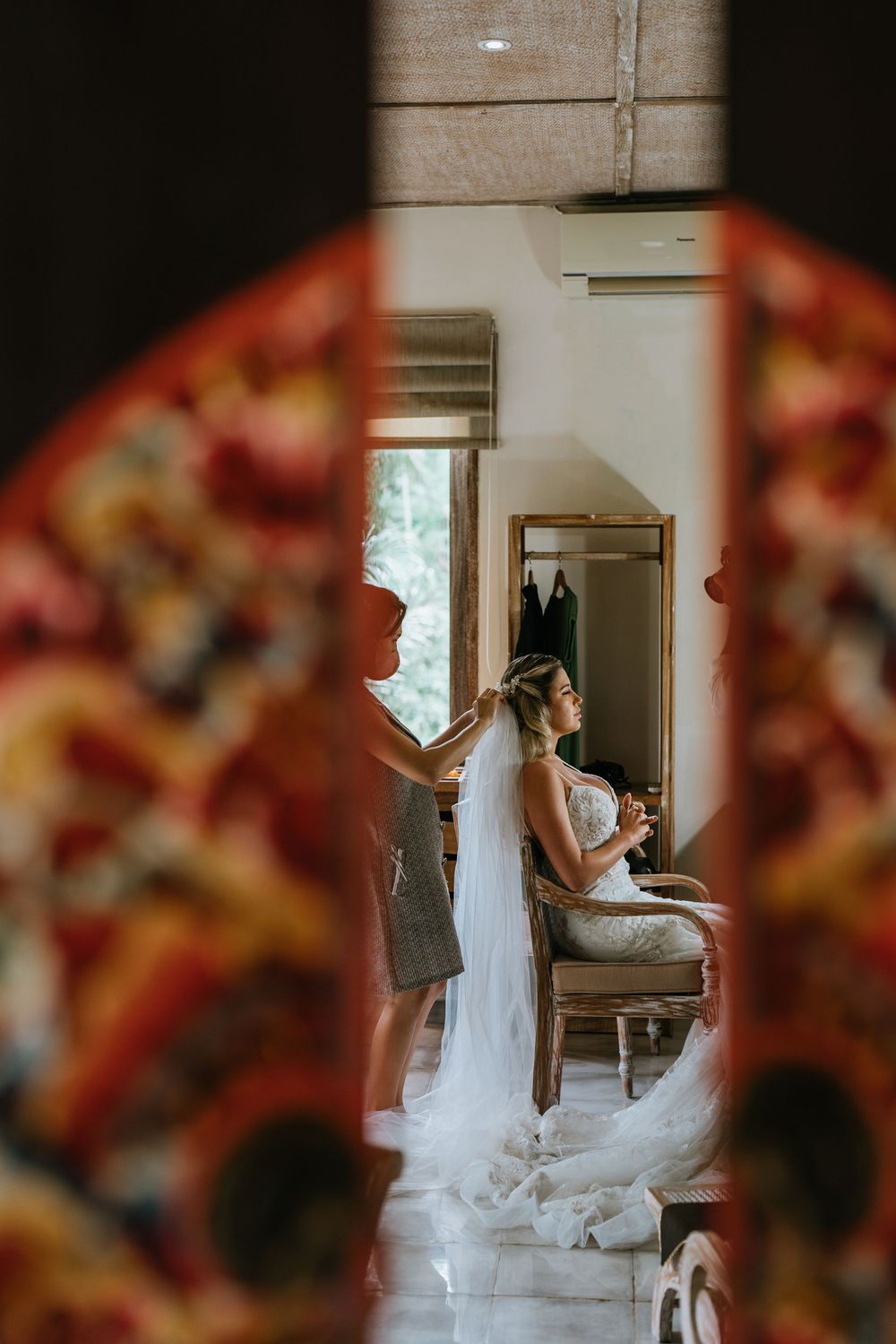 Wedding dress preparations in a sunlit room with vintage decor and floral elements.