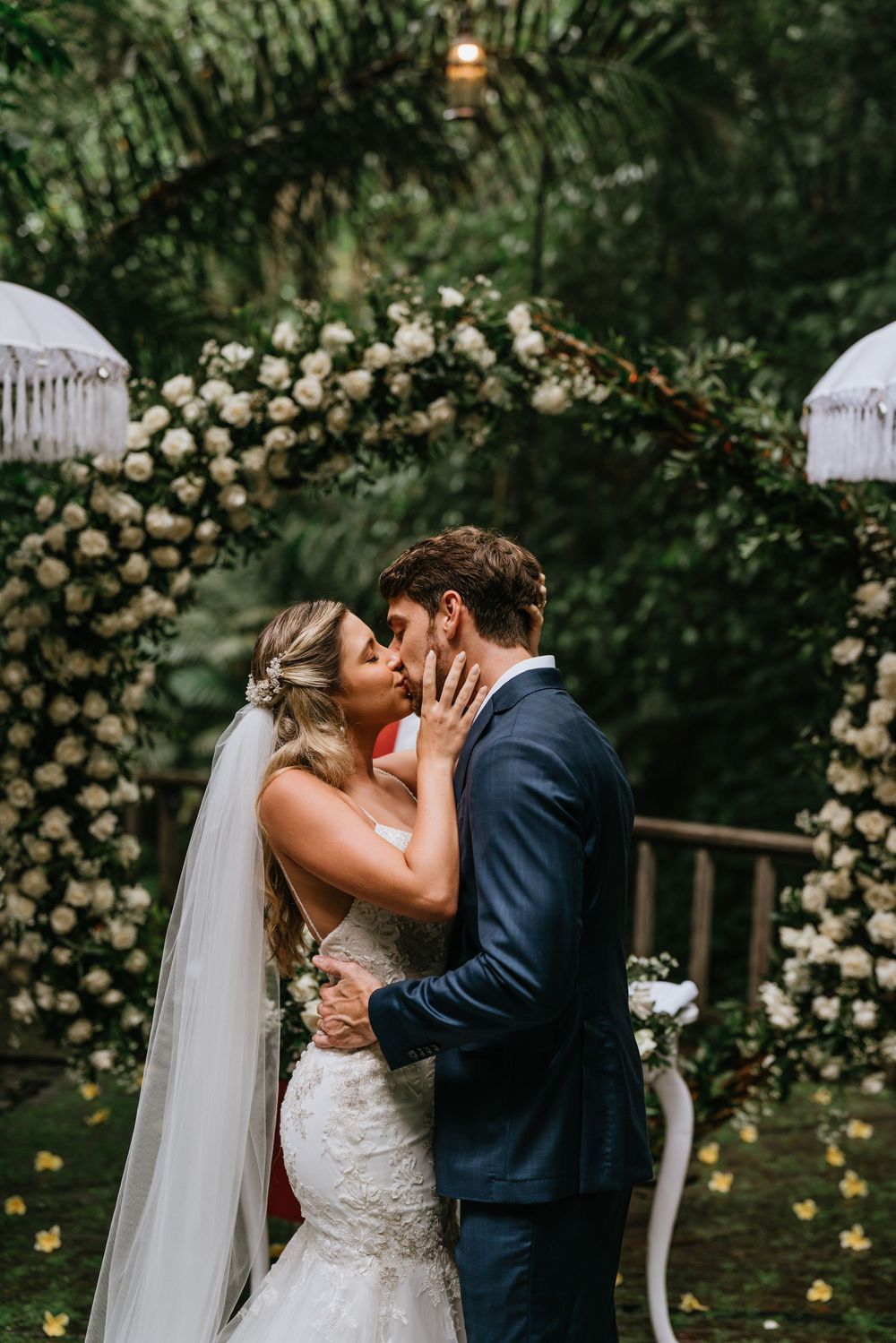 Romantic wedding moment in a garden setting with white rose archway.