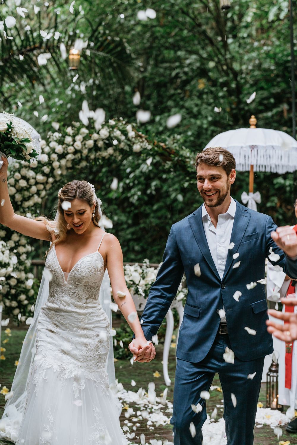 Joyful wedding celebration with flower petals in a garden setting.