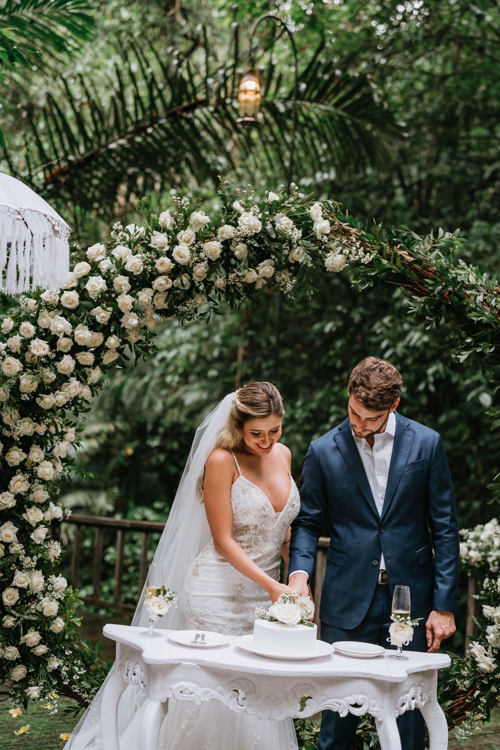 Wedding ceremony signing moment at elegant white table with floral backdrop.
