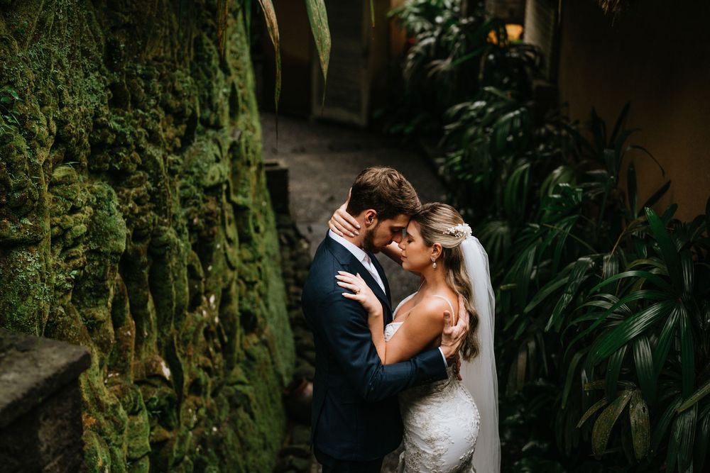 Intimate wedding moment in a lush garden setting with stone architecture.