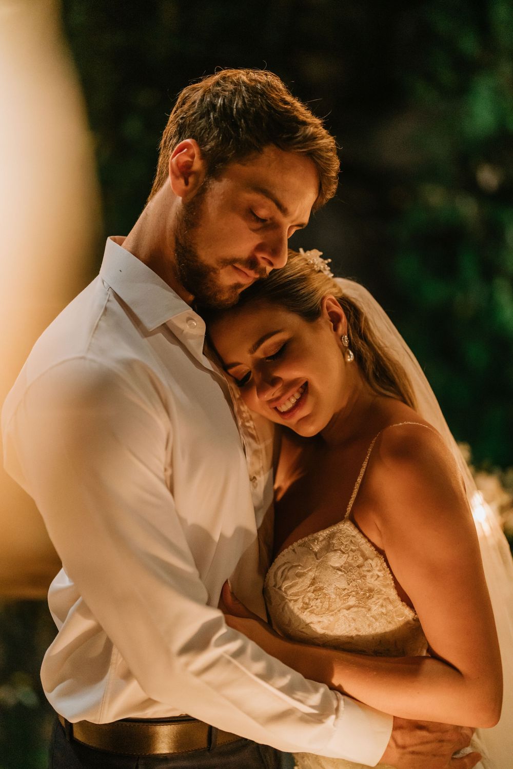 A tender moment between newlyweds sharing a romantic dance in warm lighting.