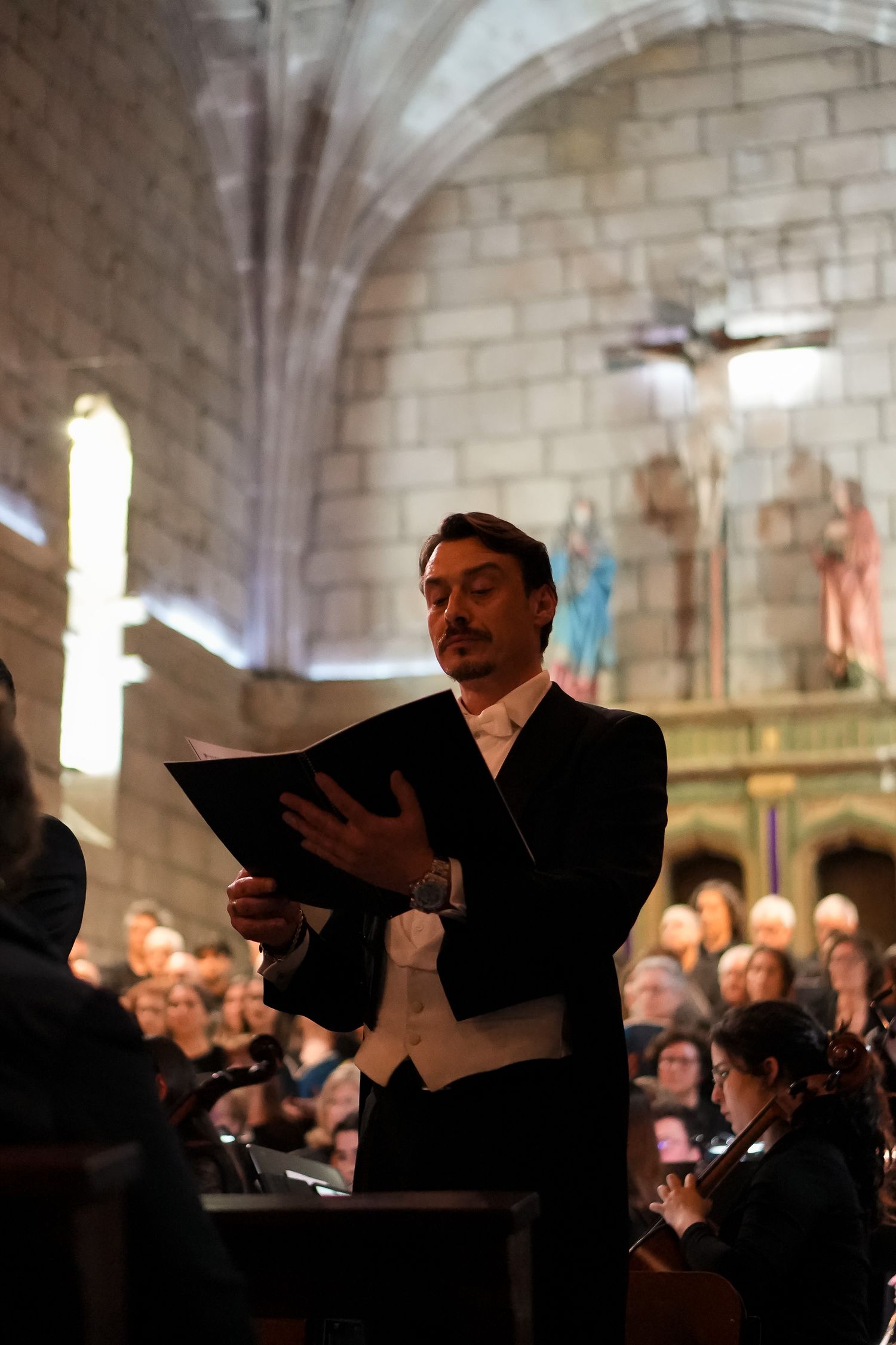 Classical performance in a stone church with musicians and conductor.