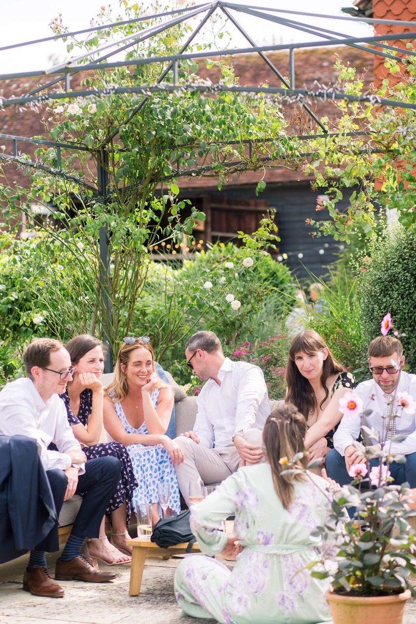 Wedding reception guests enjoying themselves under a tent in a garden setting.