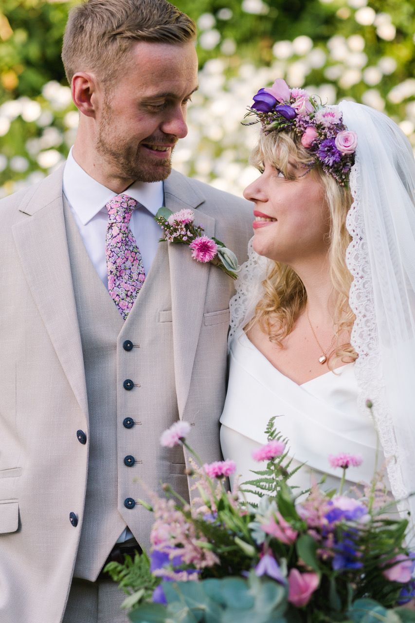 Romantic wedding portrait with purple floral accents and light gray suits.